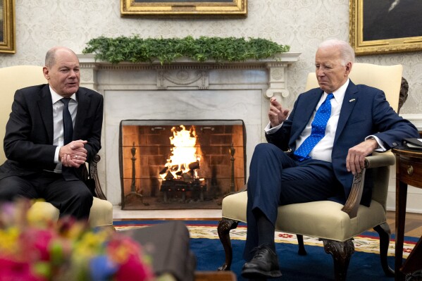 President Joe Biden, right, crosses his fingers in response to a comment from German Chancellor Olaf Scholz in the Oval Office of the White House, Friday, Feb. 9, 2024, in Washington. (AP Photo/Andrew Harnik)