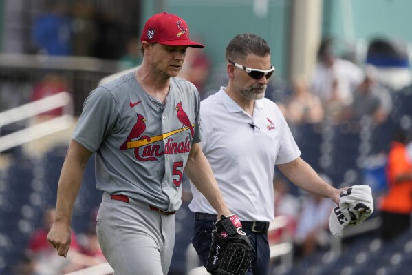 St. Louis Cardinals starting pitcher Sonny Gray, left, walks off the field with trainer Adam Olsen after being removed during the second inning of a spring training baseball game against the Washington Nationals Monday, March 4, 2024, in West Palm Beach, Fla. The team announced that Gray was removed due to tightness in his right hamstring. (AP Photo/Jeff Roberson)