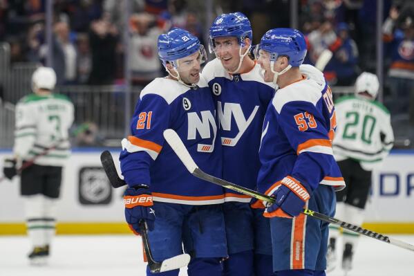 New York Islanders center Brock Nelson, center, celebrates after scoring a hat-trick goal in the third period of an NHL hockey game against the Dallas Stars, Saturday, March 19, 2022, in Elmont, N.Y. (AP Photo/John Minchillo)