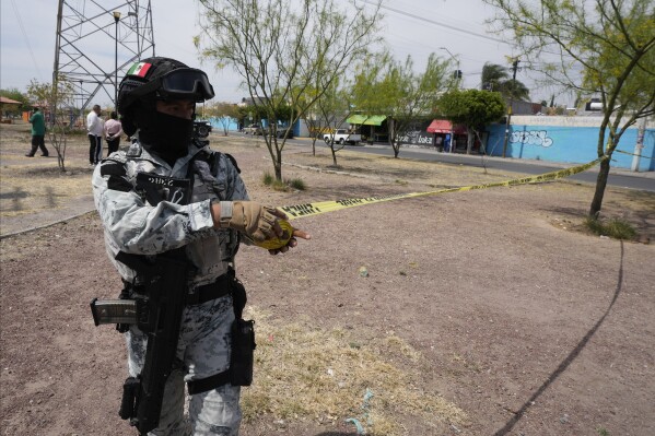 FILE - A member of the Mexican National Guard cordons off a crime scene where a passenger was shot dead inside a bus, in Celaya, Mexico, Feb. 29, 2024. As Mexico's June 2 presidential election approaches, this city lies at the crossroads of a national debate about security policy. (AP Photo/Fernando Llano, File)