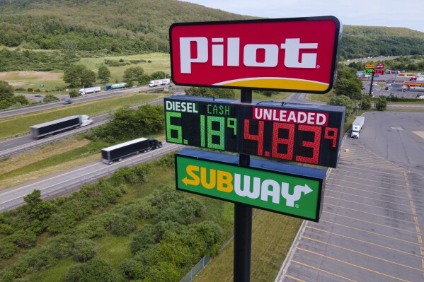 FILE - Trucks and cars drive by a Pilot Travel Center sign displaying fuel prices, June 20, 2022, in Bath, N.Y. The clock is ticking for Cleveland Browns owner Jimmy Haslam and his family to decide whether to sell their remaining stake in the Pilot truck stop chain to fellow billionaire Warren Buffet's Berkshire Hathaway company. A trial had been scheduled to start Monday, Jan. 8, 2023, in Delaware in a dispute over accounting practices at Pilot Travel Centers. (AP Photo/Ted Shaffrey, File)