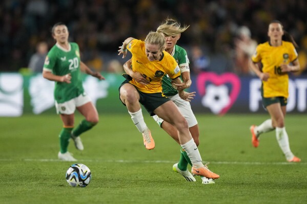 Australia's Ellie Carpenter, left, battles for the ball with Ireland's Katie McCabe during the Women's World Cup soccer game between Australia and Ireland at Stadium Australia in Sydney, Australia, Thursday, July 20, 2023. (AP Photo/Rick Rycroft)