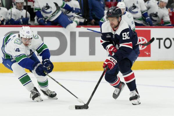 Washington Capitals center Evgeny Kuznetsov (92) skates with the puck while Vancouver Canucks defenseman Quinn Hughes (43) defends during the first period of an NHL hockey game, Monday, Oct. 17, 2022, in Washington. (AP Photo/Jess Rapfogel)