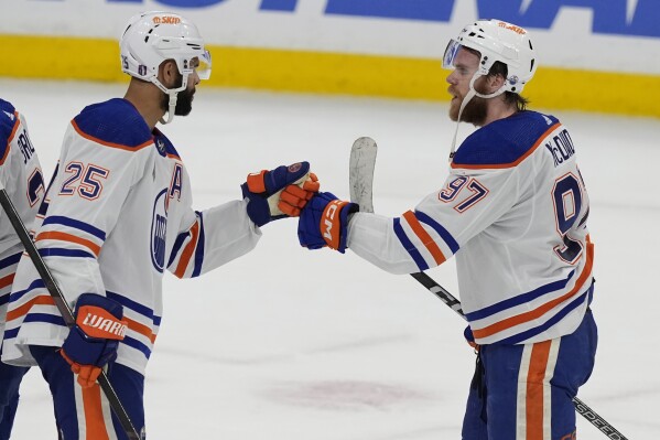 Edmonton Oilers center Connor McDavid (97) and defenseman Darnell Nurse (25) celebrate at the end of Game 5 of the NHL hockey Stanley Cup Finals against the Florida Panthers, Tuesday, June 18, 2024, in Sunrise, Fla. The Oilers defeated the Panthers 5-3. (AP Photo/Rebecca Blackwell)