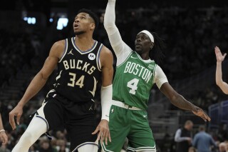 Boston Celtics' Jrue Holiday watches his shot with Milwaukee Bucks' Giannis Antetokounmpo during the first half of an NBA basketball game Tuesday, April 9, 2024, in Milwaukee. (AP Photo/Morry Gash)