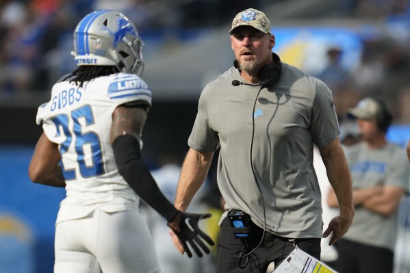 CORRECTS TO DETROIT LIONS HEAD COACH DAN CAMPBELL NOT LOS ANGELES CHARGERS HEAD COACH DAN CAMPBELL - Detroit Lions head coach Dan Campbell, right, talks to running back Jahmyr Gibbs (26) during the first half an NFL football game against the Los Angeles Chargers, Sunday, Nov. 12, 2023, in Inglewood, Calif. (AP Photo/Ashley Landis)