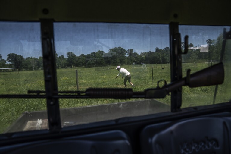 Texas rancher Hobbs Magaret steps over a fence while moving his cattle to a different grazing area in Lufkin, Texas, Monday, April 17, 2023. Magaret grew up around cattle in the west Texas panhandle, and he worked on ranches during summers home after he left to attend college. He calls himself a punk rock rancher, and he has adopted the ideas of regenerative ranching and then pushed the theory to an extreme on his 300-acre ranch. Magaret moves his 42 cows three or four times a day, sometimes shifting an electrified fence only 20 feet or so to give the animals access to new grass. (AP Photo/David Goldman)