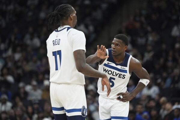 Minnesota Timberwolves center Naz Reid (11) and guard Anthony Edwards (5) high-five during the second half of an NBA basketball game against the Detroit Pistons, Wednesday, March 27, 2024, in Minneapolis. (AP Photo/Abbie Parr)