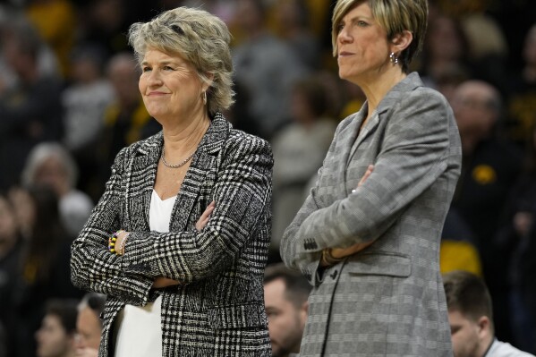 FILE - Iowa head coach Lisa Bluder, left, stands with associate head coach Jan Jensen, right, before an NCAA college basketball game against Nebraska, Saturday, Jan. 27, 2024, in Iowa City, Iowa. Bluder announced Monday, May 13, 2024, she is retiring after leading the Hawkeyes for 24 seasons. Jensen, longtime assistant to Bluder, was named the new head coach of the Iowa women's basketball team. (AP Photo/Charlie Neibergall, File)