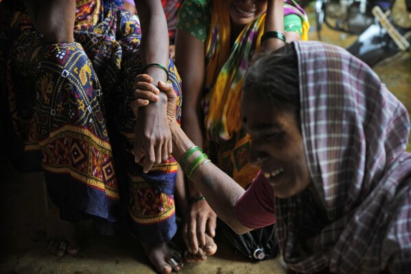 FILE - A woman holds the hand of her relative as family members of people trapped under rubble wail after a landslide washed away houses in Raigad district, western Maharashtra state, India, July 20, 2023. The devastation of this year's monsoon season in India, which runs from June to September, has been significant. (AP Photo/Rafiq Maqbool)