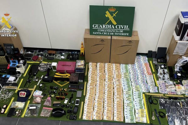 In this photo provided by the Guardia Civil on Friday Dec. 15, 2023, items stolen from suitcases are displayed on the Canary island of Tenerife, Spain. Spanish police say they have arrested 14 workers at one of the country's main tourist airports on suspicion of stealing items from checked-in luggage. Police seized allegedly stolen items worth almost 2 million euros ($2.2 million) from the group of employees at the largest airport in Tenerife, in Spain's Canary Islands. (Guardia Civil via AP)
