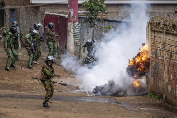 Kenyan riot police react as a tear gas grenade they threw explodes next to them, during clashes with rock-throwing opposition protesters in the Kibera slum of the capital Nairobi, Kenya Tuesday, May 2, 2023. The fresh round of demonstrations called by opposition leader Raila Odinga demanded action to tackle the cost of living and reforms to the electoral commission that oversaw last year's election that was won by President William Ruto. (AP Photo/Ben Curtis)