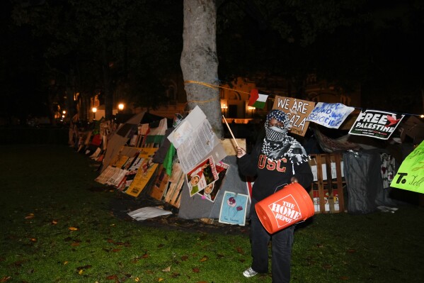 Um manifestante fica em frente a um acampamento montado por manifestantes pró-palestinos no campus da Universidade do Sul da Califórnia depois que a polícia chegou com uma ordem de dispersão, domingo, 5 de maio de 2024, em Los Angeles.  (Foto AP / Ryan Sun)