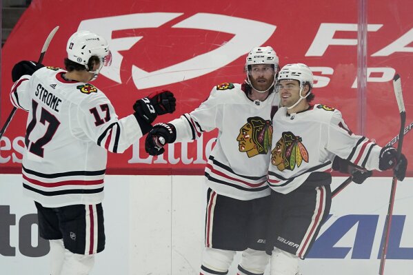 Chicago Blackhawks center Dylan Strome (17), defenseman Duncan Keith (2) and left wing Alex DeBrincat (12) celebrate a goal by Keith during the first period of an NHL hockey game against the Detroit Red Wings, Thursday, April 15, 2021, in Detroit. (AP Photo/Carlos Osorio)