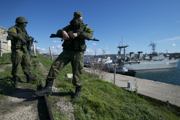 Russian soldiers guard a pier where two Ukrainian naval vessels are moored, in Sevastopol, on the Crimean Peninsula, March 5, 2014. (AP Photo, File)