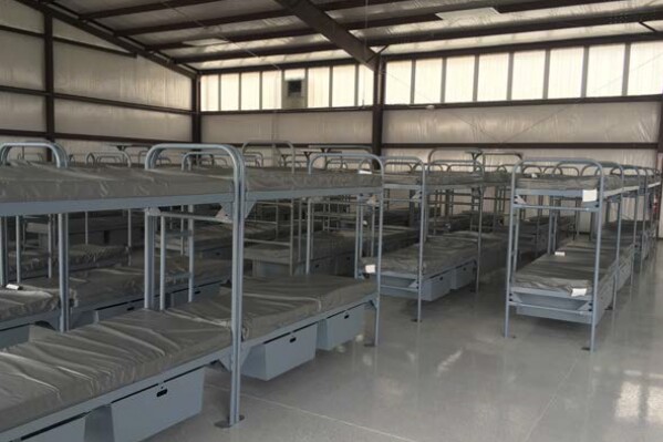 Bunkbeds, used by prison workers who were relocated to Hickman's Family Farms during the COVID-19 pandemic, sit in close rows inside a metal hangar-like warehouse at the farm in Arlington, Ariz. In March 2020, though all other private outside jobs were halted, the Arizona corrections department announced about 140 women were being abruptly moved from their prison to the makeshift dormitory on the property owned by Hickman's, which pitches itself as the Southwest's largest egg producer. (Arizona Correctional Industries via AP)