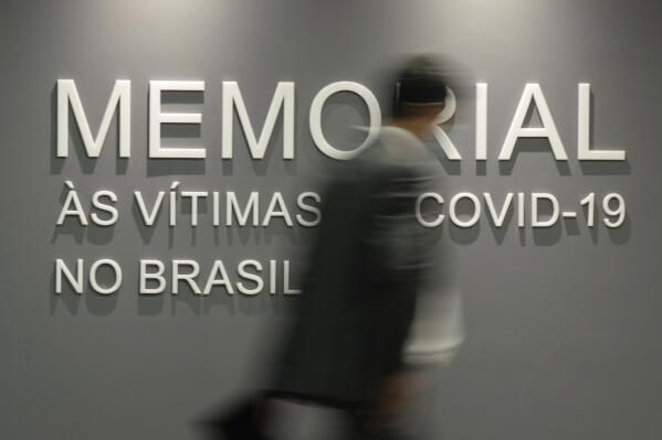 FILE - A man walks past a wall that reads in Portuguese "Memorial to the victims of COVID-19 in Brazil," in the Senate building in Brasilia, Brazil, Tuesday, Feb. 15, 2022. Brazil has officially recorded its 700,000th death from COVID-19, on Tuesday, March 28, 2023. (AP Photo/Claudio Reis, File)