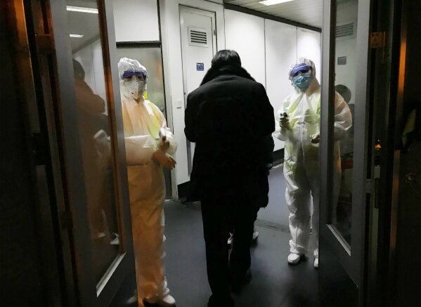 Health Officials in hazmat suits wait at the gate to check body temperatures of passengers arriving from the city of Wuhan Wednesday, Jan. 22, 2020, at the airport in Beijing, China. Nearly two decades after the disastrously-handled SARS epidemic, China’s more-open response to a new virus signals its growing confidence and a greater awareness of the pitfalls of censorship, even while the government is as authoritarian as ever. (AP Photo Emily Wang)