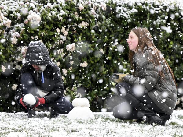 Brody Mielke, left, 10, and his older sister Braelynn, 12, make a snowman as snow falls at approximately the 1,700 foot level in front of their Fontana, Calif., home in Hunters Ridge on Saturday, Feb. 25, 2023. (Will Lester/The Orange County Register via AP)