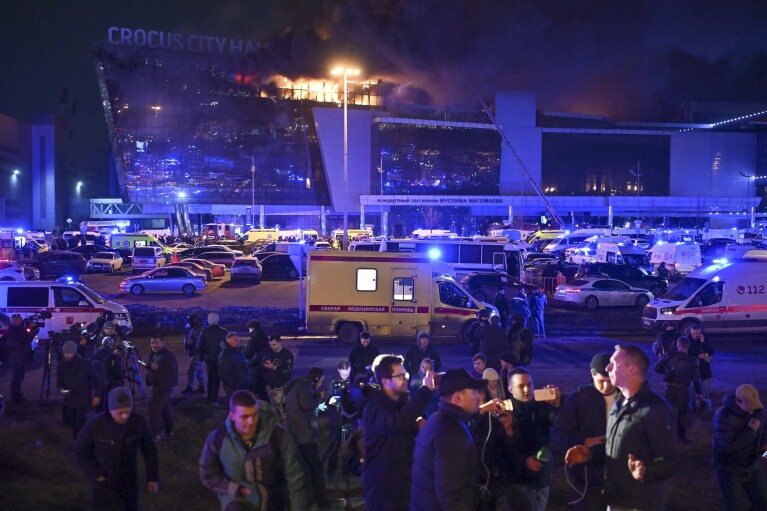 A man speaks to journalists as a massive blaze seen over the Crocus City Hall on the western edge of Moscow, Russia, Friday, March 22, 2024. Several gunmen have burst into a big concert hall in Moscow and fired automatic weapons at the crowd, injuring an unspecified number of people and setting a massive blaze in an apparent terror attack days after President Vladimir Putin cemented his grip on the country in a highly orchestrated electoral landslide. (AP Photo/Dmitry Serebryakov)