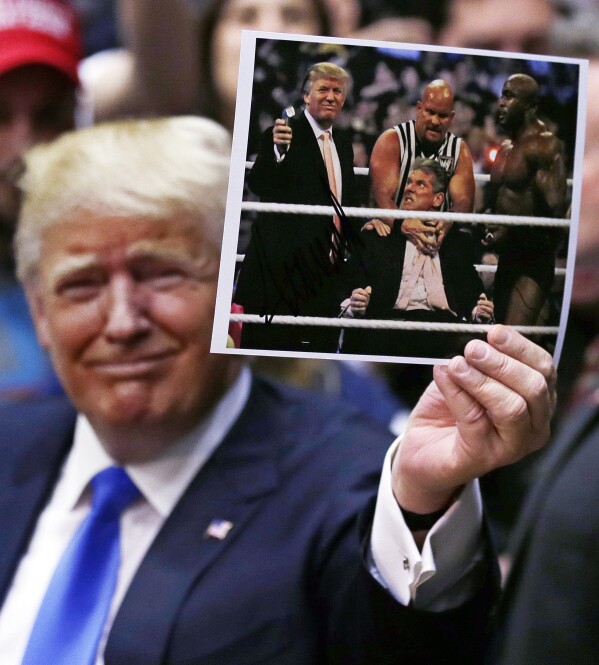FILE - Republican presidential candidate Donald Trump holds up a photograph of him participating in WrestleMania during a campaign event at Crosby High School in Waterbury, Conn., Saturday, April 23, 2016. (AP Photo/Charles Krupa, File)