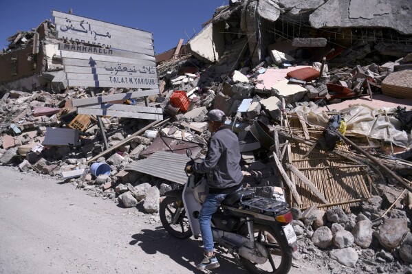 A man on a scooter drives past rubble and a damaged road sign pointing to Marrakech in Talat N'yakoub, Morocco, Monday Sept. 11, 2023. More than 2,000 people were killed, and the toll was expected to rise as rescuers struggled to reach hard-hit remote areas after a powerful earthquake struck Morocco. (Fernando Sanchez/Europa Press via AP)