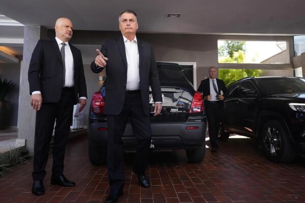 Former Brazilian President Jair Bolsonaro speaks to the press outside his house after Federal Police agents carried out a search and seizure warrant in Brasilia, Brazil, Wednesday, May 3, 2023. When asked about the search of Bolsonaro’s home in Brasilia, the Federal Police press office gave a statement saying officers were carrying out searches and arrests related to the introduction of fraudulent data related to the COVID-19 vaccine into the nation’s health system. (AP Photo/Eraldo Peres)