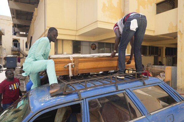 People move the coffin of their friend, Abdou Diop, who died trying to migrate to Europe, at the Saint Louis, Senegal, morgue Saturday, July 15, 2023. More people are making the trip across the Atlantic in rickety wooden boats known as pirogues trying to reach the Canary Islands. (AP Photo/Sam Mednick)