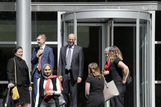 FILE - In this June 28, 2019, file photo, Matt Adams, center right, Legal Director of the Northwest Immigrant Rights Project, leaves the U.S. Courthouse with others after a hearing on asylum seekers in Seattle. On Tuesday, July 2, 2019, a federal judge in Seattle has blocked a Trump administration policy that would keep thousands of asylum seekers locked up while they pursue their cases. (AP Photo/Elaine Thompson, File)