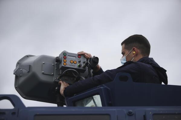 Police officer Dimitris Bistinas operates a long range acoustic device, (LRAD), attached on a police vehicle, during a patrol alongside the Greek - Turkish border near the town of Feres, Greece, Friday, May 21, 2021. An automated hi-tech surveillance network being built on the Greek-Turkish border aiming at detecting migrants early and deterring them from crossing, with river and land patrols using searchlights and long-range acoustic devices. (AP Photo/Giannis Papanikos)