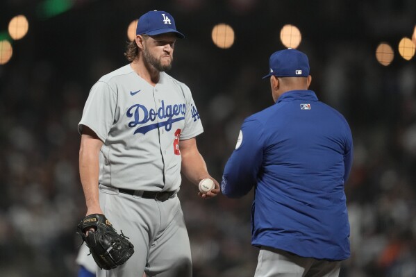 Los Angeles Dodgers pitcher Clayton Kershaw, left, hands the ball to manager Dave Roberts during a pitching change in the sixth inning of the team's baseball game against the San Francisco Giants in San Francisco, Saturday, Sept. 30, 2023. (AP Photo/Jeff Chiu)