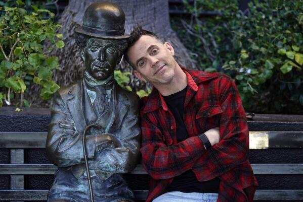 Steve-O, a cast member in the film "Jackass Forever," poses alongside a statue of silent movie great Charlie Chaplin on a bench at The Hollywood Roosevelt, Thursday, Jan. 27, 2022, in Los Angeles. (AP Photo/Chris Pizzello)