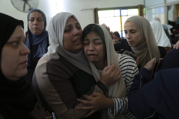 Mourners cry after taking the last look at the body of Mahmoud Abu Saan, 18, at a mosque during his funeral in the West Bank city of Tulkarem, Friday, Aug. 4, 2023. Israeli security forces killed Abu Saan during a military raid into the northern West Bank on Friday, Palestinian health officials said. The Israeli army said soldiers shot at Palestinians in Tulkarem who threw stones and explosives at them. (AP Photo/Nasser Nasser)