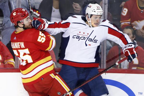 Washington Capitals' Nic Dowd, right, works against Calgary Flames' Noah Hanifin during the second period of an NHL hockey game Tuesday, March 8, 2022, in Calgary, Alberta. (Larry MacDougal/The Canadian Press via AP)