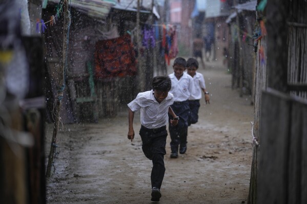 Children run to school in the rain in Gardi Sugdub Island, part of the San Blas archipelago off Panama's Caribbean coast, Monday, May 27, 2024. Due to rising sea levels, about 300 Guna Indigenous families will relocate to new homes, built by the government, on the mainland. (AP Photo/Matias Delacroix)