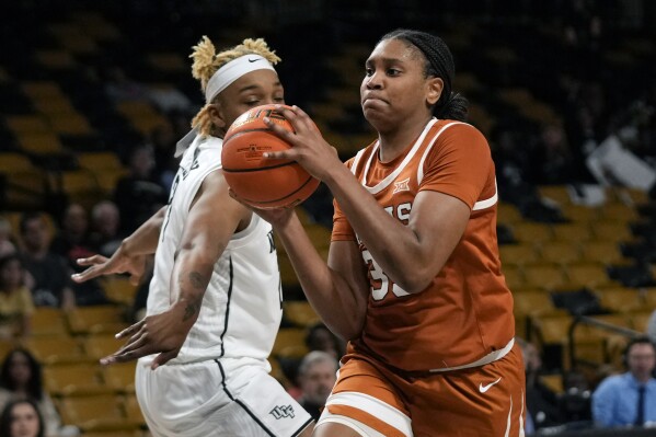 Texas forward Madison Booker, right, goes to the basket past Central Florida center Jayla Kelly for a shot during the second half of an NCAA college basketball game, Saturday, Feb. 24, 2024, in Orlando, Fla. (AP Photo/John Raoux)