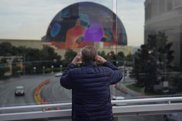 FILE - A person stops to take a picture of the Sphere on a pedestrian bridge along the Las Vegas Strip, Wednesday, Jan. 17, 2024, in Las Vegas. The American Civil Liberties Union of Nevada announced Friday, Feb. 16, that it had filed a legal challenge to a controversial ban on stopping or standing on Las Vegas Strip pedestrian bridges. (AP Photo/John Locher, File)