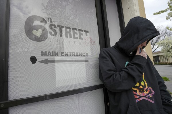 Solace Kalkowski, who was sleeping in a truck after a breakup a few weeks ago, stands outside the 6th Street Center for Youth in Chico, Calif., Feb. 8, 2024. A measure aimed at transforming how California spends money on mental health will go before voters in March as the state continues to grapple an unabated homelessness crisis. Kalkowski said the center kept them from ending up chronically homeless. The 6th Street Center for Youth, Chico's only drop-in center for troubled youths at risk, also offers rent assistance to college students. But workers at 6th Street, do not believe that would protect it from funding cuts if Proposition 1 is approved..(AP Photo/Rich Pedroncelli)