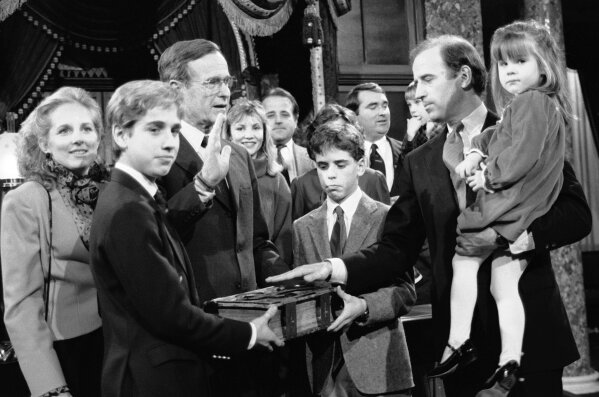 FILE - In this Jan. 3, 1985 file photo, Sen. Joe Biden, D-Del., holds his daughter Ashley while taking a mock oath of office from Vice President George Bush during a ceremony on Capitol Hill, in Washington. Biden's sons Beau and Hunt hold the bible during the ceremony. (AP Photo/Lana Harris, File)