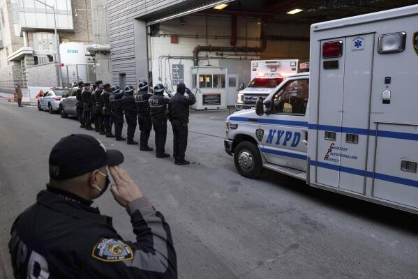 New York Police Department officers salute during the transfer of the remains of officer Wilbert Mora outside the NYU Langone hospital in New York, Tuesday, Jan. 25, 2022. The New York City police officer who was gravely wounded last week in a Harlem shooting that killed his partner has also died of his injuries, the city’s police commissioner said Tuesday, adding to what she called “incalculable” grief within the department.  (AP Photo/Yuki Iwamura)