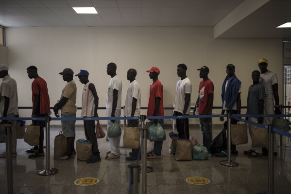 Los sobrevivientes de la piragua senegalesa que fue encontrada a la deriva hacen fila en el aeropuerto antes de abordar un vuelo para ser repatriados, en la isla de Sal, Cabo Verde, el lunes 21 de agosto de 2023. (AP Foto/Felipe Dana)