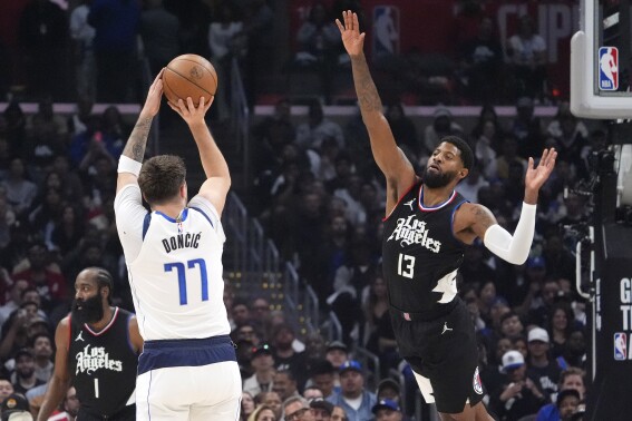 Dallas Mavericks guard Luka Doncic, center, shoots as Los Angeles Clippers forward Paul George, right, and guard James Harden defend during the first half in Game 2 of an NBA basketball first-round playoff series Tuesday, April 23, 2024, in Los Angeles. (AP Photo/Mark J. Terrill)