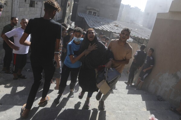 Palestinians evacuates a woman following Israeli airstrikes on town of Khan Younis, southern Gaza Strip, Thursday, Oct. 26, 2023. (AP Photo/Mohammed Dahman)