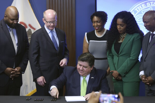 Gov. J.B. Pritzker, surrounded by lawmakers, signs the 2025 budget in Chicago on Wednesday, June 5, 2024. (Antonio Perez/Chicago Tribune via AP)
