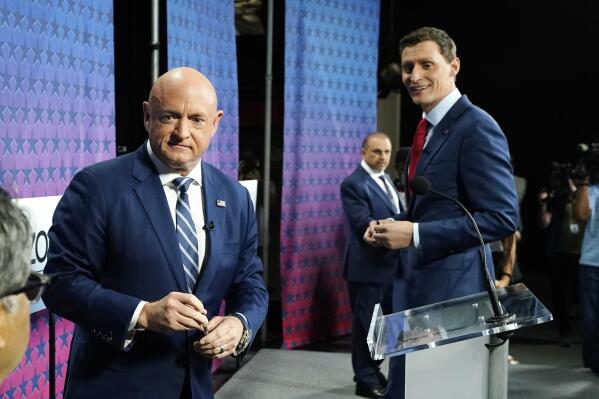 Arizona Democratic Sen. Mark Kelly, left, Republican challenger Blake Masters, right, and Libertarian Marc Victor, back, pause on the stage prior to a televised debate in Phoenix, Thursday, Oct. 6, 2022. (AP Photo/Ross D. Franklin)