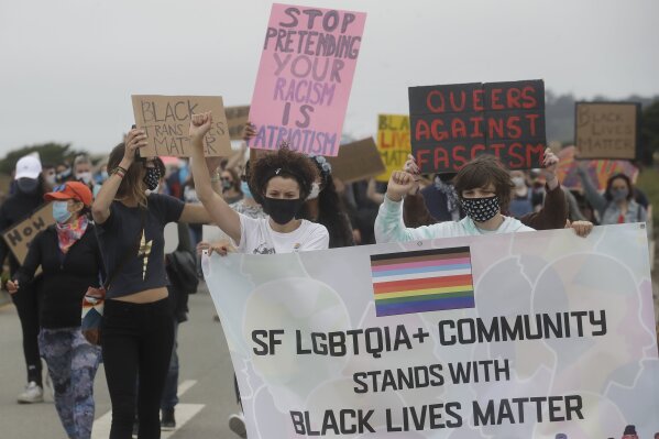 Angela Rose, center, marches with gay activists and suppoters on the Great Highway at Ocean Beach in San Francisco, Sunday, June 14, 2020, at a protest over the Memorial Day death of George Floyd, who died after being restrained by Minneapolis police. (AP Photo/Jeff Chiu)