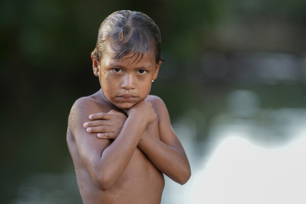 An Indigenous Wari' boy looks to the camera after swimming in the Komi Memem River, named Laje in non-Indigenous maps, in Guajara-Mirim, Rondonia state, Brazil, Thursday, July 13, 2023.  (AP Photo/Andre Penner)
