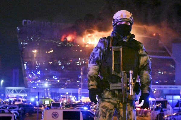 A Russian Rosguardia (National Guard) servicemen secures an area as a massive blaze seen over the Crocus City Hall on the western edge of Moscow, Russia, Friday, March 22, 2024. Several gunmen have burst into a big concert hall in Moscow and fired automatic weapons at the crowd, injuring an unspecified number of people and setting a massive blaze in an apparent terror attack days after President Vladimir Putin cemented his grip on the country in a highly orchestrated electoral landslide. (AP Photo/Dmitry Serebryakov)