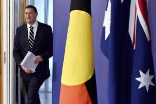 Australian lawmaker Julian Leeser walks past the Australian flag, right, and the Aboriginal flag on his arrival for a press conference in Sydney, Tuesday, April 11, 2023. Leeser has spilt from Australia's opposition party leadership by supporting the government's proposal to create a so-called Indigenous Voice to Parliament. (Bianca De Marchi/AAP Image via AP)