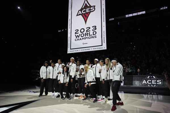 Las Vegas Aces players pose as they raise the 2023 championship banner before a WNBA basketball game Tuesday, May 14, 2024, in Las Vegas. (AP Photo/John Locher)